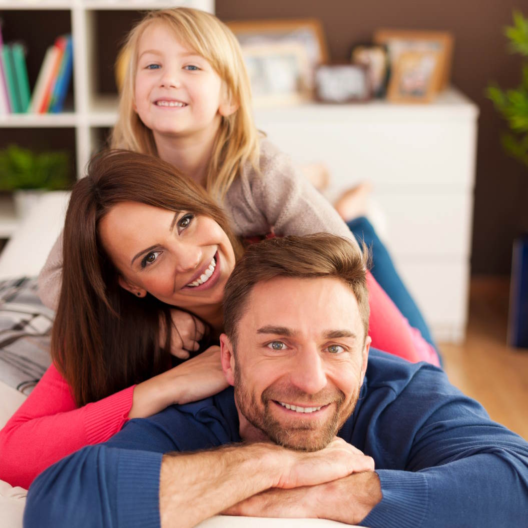 Vater, Mutter und Kind lächeln in die Kamera als Sinnbild für die Asicherung durch eine Berufsunfähigkeitsversicherung