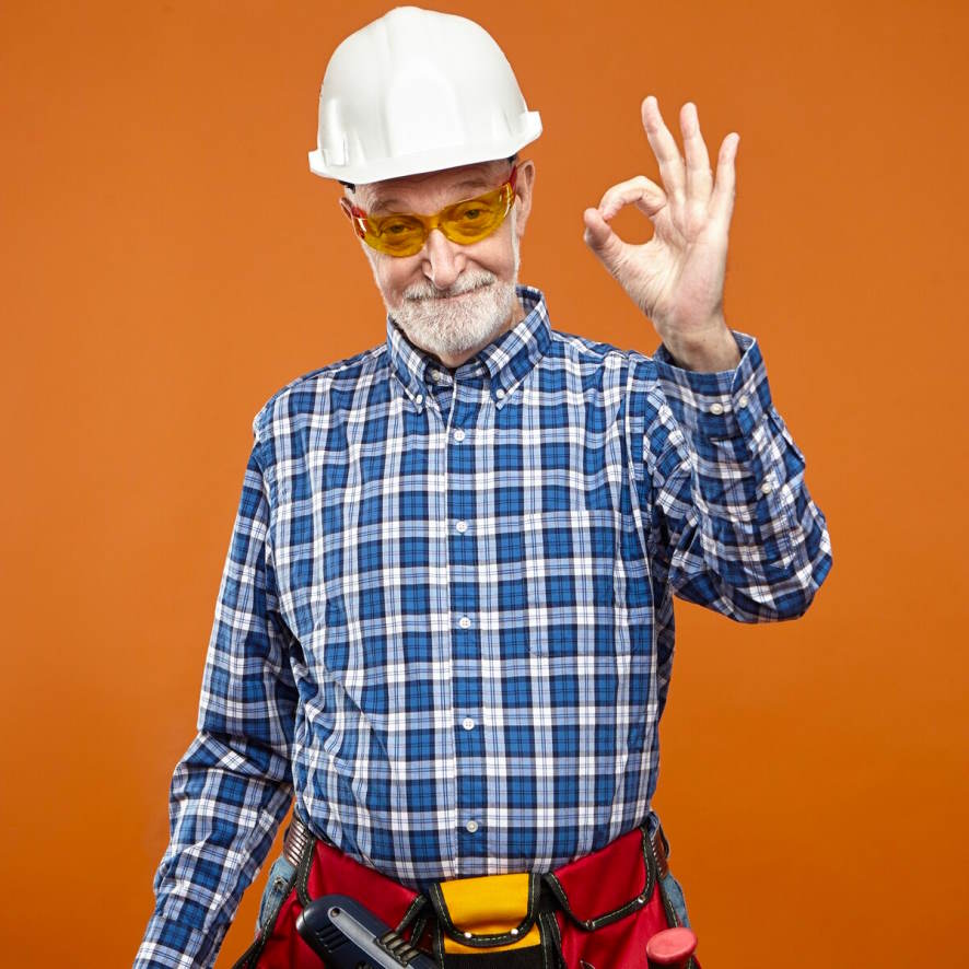 Ein Bauarbeiter steht vor orangenen Hintergrund und gibt das “Ok”-Zeichen, als Sinnbild für die Zufriedenheit mit der betrieblichen Altersvorsorge
