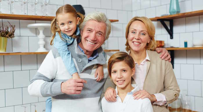 Foto zeigt eine lächelnde Familie in der Küche. Das steht als Sinnbild für eine Altersvorsorge durch die Riester Rente